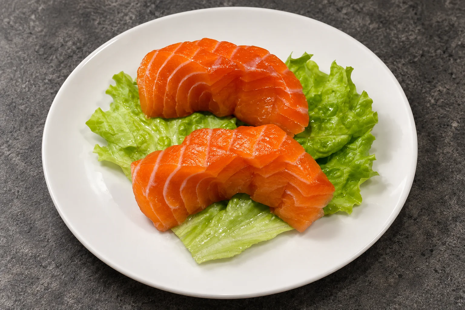 Sashimi saumon sur feuilles de salade, assiette blanche, fond de béton sombre.