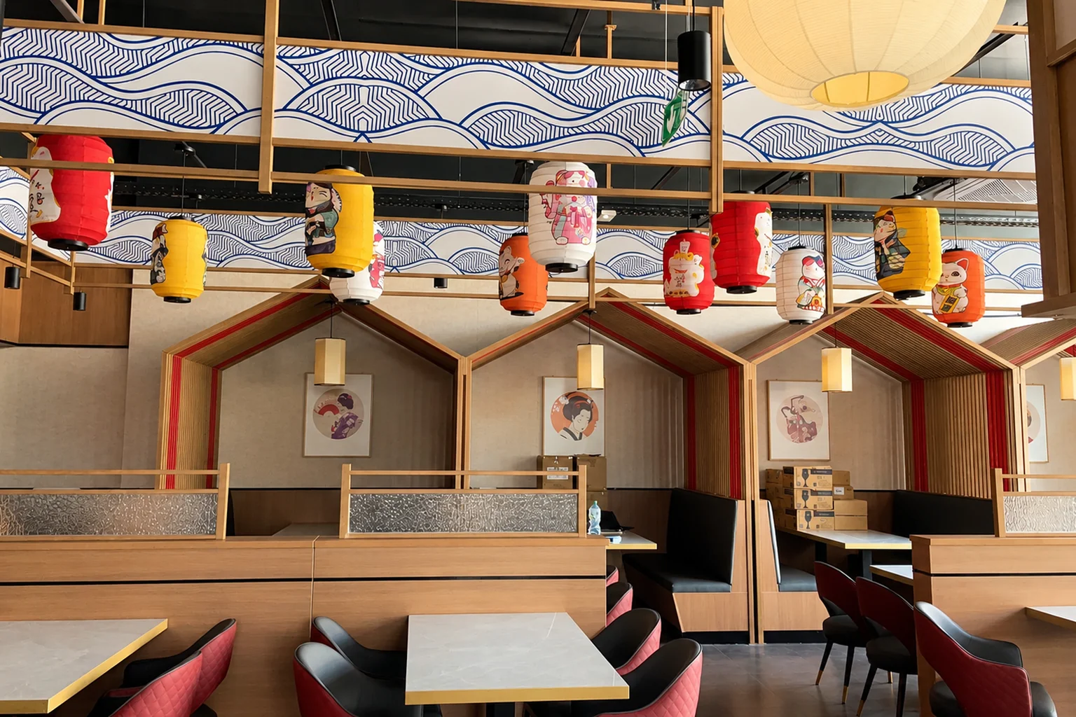 Rangée de box en bois en forme de petites maisons, tables et chaises, lanternes au plafond.