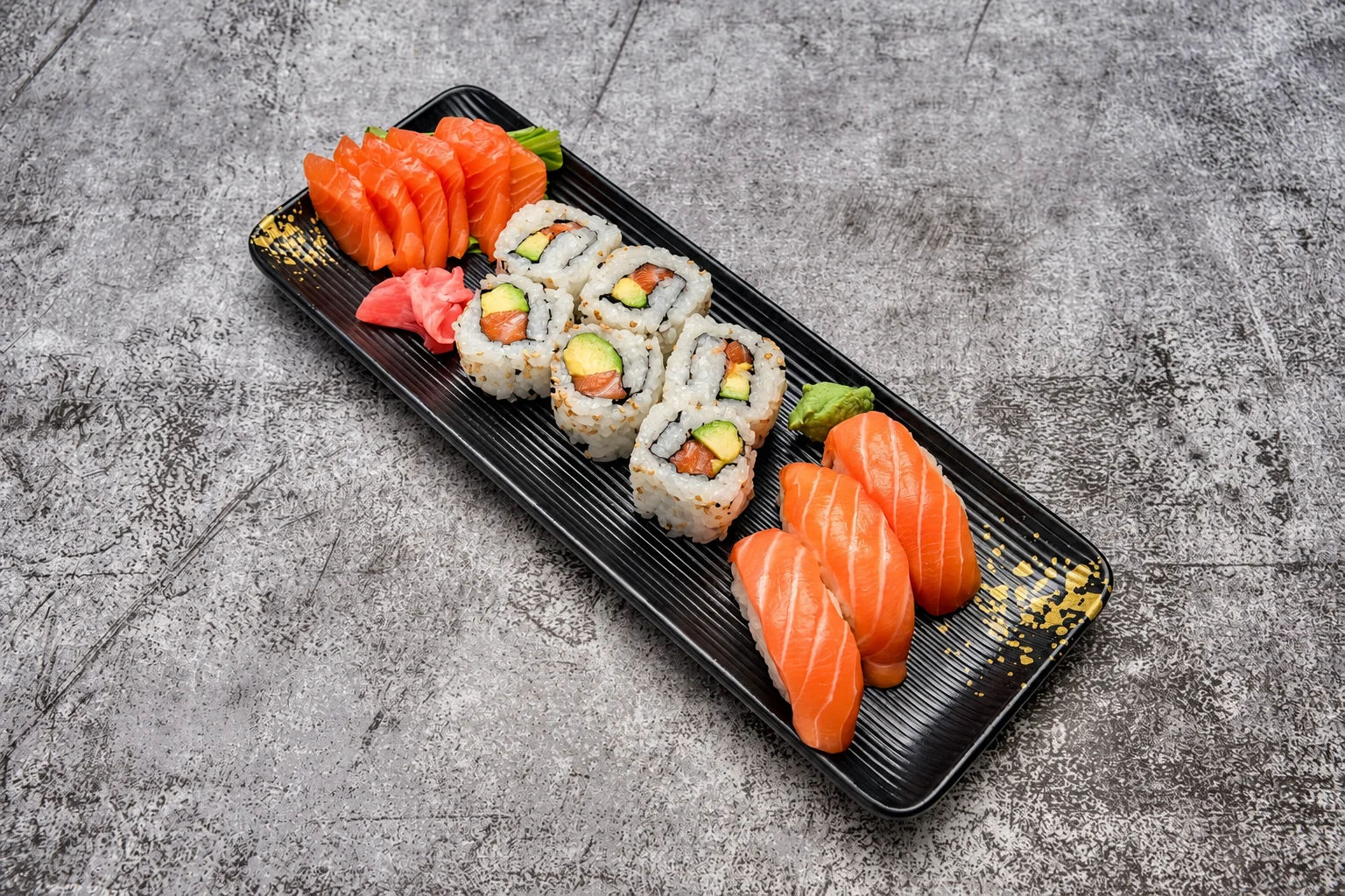 Sashimi saumon, california et nigiri saumon sur une assiette noire striée, fond de béton gris.